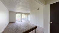 This 2-bedroom, 2-bathroom residence is laid out on a single floor, offering a well-organized and functional living environment. The combined dining and living room serves as the heart of the home, featuring wall-to-wall carpet, a textured ceiling, and large sliding glass doors dressed with vertical blinds that open to an outdoor balcony and frame lush green tree views, filling the space with natural light. A railed staircase landing connects the main living area to the entrance below, adding a subtle architectural detail to the open layout.

The kitchen is equipped with white cabinetry, laminate countertops, a tile backsplash, a gas range with overhead ventilation, and a stainless steel sink, all set on hardwood-style flooring. Two full bathrooms serve the unit — one featuring a single-sink vanity with a tiled tub-shower combo and hardwood-style flooring, and the other with a vanity topped with a stone-toned countertop and tiled surroundings.

Both bedrooms are carpeted and bathed in natural light through large windows with outdoor views. The primary bedroom offers a comfortable footprint with ample wall space. Five closets throughout the unit provide generous storage. A dedicated hallway connects the private areas of the home, contributing to a clear and practical floor plan.