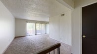 This 2-bedroom, 2-bathroom residence is laid out on a single floor, offering a well-organized and functional living environment. The combined dining and living room serves as the heart of the home, featuring wall-to-wall carpet, a textured ceiling, and large sliding glass doors dressed with vertical blinds that open to an outdoor balcony and frame lush green tree views, filling the space with natural light. A railed staircase landing connects the main living area to the entrance below, adding a subtle architectural detail to the open layout.

The kitchen is equipped with white cabinetry, laminate countertops, a tile backsplash, a gas range with overhead ventilation, and a stainless steel sink, all set on hardwood-style flooring. Two full bathrooms serve the unit — one featuring a single-sink vanity with a tiled tub-shower combo and hardwood-style flooring, and the other with a vanity topped with a stone-toned countertop and tiled surroundings.

Both bedrooms are carpeted and bathed in natural light through large windows with outdoor views. The primary bedroom offers a comfortable footprint with ample wall space. Five closets throughout the unit provide generous storage. A dedicated hallway connects the private areas of the home, contributing to a clear and practical floor plan.