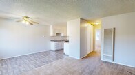 This single-floor unit in Suisun City, California offers a practical and functional layout designed for comfortable everyday living. The open-concept living and dining area is finished with wood-look vinyl plank flooring and features a ceiling fan with light fixture, a wall-mounted air conditioning unit, and a textured ceiling throughout. Natural light filters in through a large window, offering views of surrounding greenery and creating a bright, airy atmosphere.

The kitchen flows directly off the living area and is equipped with white cabinetry featuring raised-panel detailing, laminate countertops, a stainless steel refrigerator, a dishwasher, and a double-basin sink. The layout provides ample counter and storage space for everyday cooking needs.

The bedroom is generously sized with plush carpet flooring, a large window that invites natural light, and direct access to a dedicated vanity area complete with a mirrored medicine cabinet, white cabinetry, and a well-lit countertop sink. An additional door leads to a separate bathroom space. A wall-mounted HVAC unit ensures climate control throughout. The textured ceilings and neutral wall tones give the entire unit a clean, move-in ready appearance.