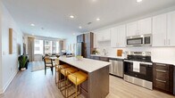 This thoughtfully designed one-bedroom, one-bathroom residence at 3606 Rainbow Blvd in Kansas City, Kansas, offers a cohesive open-concept layout that maximizes every square foot. The kitchen is a standout feature, showcasing a striking two-tone cabinetry scheme pairing crisp white upper cabinets with rich dark wood lower cabinets. A large quartz-topped island with seating flows naturally into the dining and living areas, making it ideal for entertaining. Stainless steel appliances, a subway tile backsplash, and light wood-style flooring complete the modern aesthetic. The living room is bright and inviting, with oversized windows that flood the space with natural light and provide views of the surrounding community. A private balcony access door adds an outdoor element to the living area. The bedroom offers a comfortable, carpeted retreat with a large window, ample natural light, and direct access to a well-organized closet. The bathroom features elegant marble-look tile flooring, a dark wood vanity with quartz countertop, and a glass-enclosed shower, creating a clean and sophisticated finish. Recessed lighting throughout ties the entire residence together with a polished, contemporary feel.