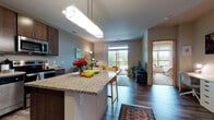 Located at 3308 University Ave in Shorewood Hills, WI, this single-floor residence offers a thoughtfully designed open-concept layout that connects the kitchen, dining, and living areas into one cohesive space. Rich hardwood-style flooring runs throughout the main living areas, complementing the warm, neutral color palette on the walls.

The kitchen is well-equipped with dark espresso cabinetry, granite countertops, and a full suite of stainless steel appliances, including a refrigerator, range, microwave, and dishwasher. A peninsula with seating provides additional workspace and serves as a natural divider between the kitchen and living area.

The living room is oriented toward a sliding glass door that opens to a private balcony overlooking a lush, green outdoor setting, allowing generous natural light to fill the space. The bedroom features carpeted flooring, a ceiling fan, and its own window with outdoor views, providing a comfortable and quiet retreat.

The bathroom includes a walk-in shower and is conveniently located adjacent to an in-unit stacked washer and dryer, adding practical functionality. Overall, the space presents a modern, comfortable layout suited for everyday living.