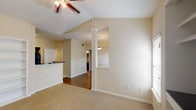 This single-story, 2-bedroom, 2-bathroom residence offers a thoughtfully designed layout with a blend of functional and architectural details. The living area stands out with vaulted ceilings accented by a ceiling fan, built-in shelving for display or storage, and multiple windows that invite natural light. A decorative column and pendant light define the transition between the living space and dining area, while hardwood-style flooring extends through the main living zones.

The kitchen is equipped with dark espresso cabinetry, dark granite-style countertops, and a full suite of black appliances including a range, microwave, dishwasher, and refrigerator. A wraparound peninsula provides additional counter space and a casual breakfast bar, opening conveniently to the living and dining areas. Light tile flooring completes the kitchen's practical aesthetic.

Both bedrooms are carpeted and well-sized, each with ceiling fixtures and windows fitted with blinds. The bathrooms are finished with dark vanity cabinetry, contrasting countertops, large mirrors, and tiled tub-shower combinations with curved curtain rods. Hardwood-style flooring carries through the bathroom spaces, adding a cohesive design element throughout the home.