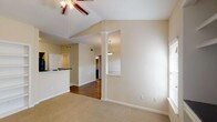 This single-story, 2-bedroom, 2-bathroom residence offers a thoughtfully designed layout with a blend of functional and architectural details. The living area stands out with vaulted ceilings accented by a ceiling fan, built-in shelving for display or storage, and multiple windows that invite natural light. A decorative column and pendant light define the transition between the living space and dining area, while hardwood-style flooring extends through the main living zones.

The kitchen is equipped with dark espresso cabinetry, dark granite-style countertops, and a full suite of black appliances including a range, microwave, dishwasher, and refrigerator. A wraparound peninsula provides additional counter space and a casual breakfast bar, opening conveniently to the living and dining areas. Light tile flooring completes the kitchen's practical aesthetic.

Both bedrooms are carpeted and well-sized, each with ceiling fixtures and windows fitted with blinds. The bathrooms are finished with dark vanity cabinetry, contrasting countertops, large mirrors, and tiled tub-shower combinations with curved curtain rods. Hardwood-style flooring carries through the bathroom spaces, adding a cohesive design element throughout the home.