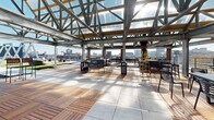 Located at 417 Callowhill Street in Philadelphia's vibrant Northern Liberties neighborhood, this rooftop amenity level offers a richly appointed outdoor experience with sweeping panoramic views of the Philadelphia skyline, the Benjamin Franklin Bridge, and the Delaware River beyond. The space is organized into several distinct zones, each designed for a different type of social or recreational use. A generously sized artificial turf area anchors one section of the roof, framed by striking A-frame steel structural trusses that lend the space an industrial-chic character. Concrete pathways connect the various activity areas, which include outdoor swing seating, lounge furniture, and open gathering spaces. A covered pavilion with exposed wood-plank cathedral ceilings and steel truss framing provides a sheltered dining and seating area, open to the skyline on multiple sides. Separate pergola-covered lounge zones feature teak wood deck tiles and contemporary outdoor furniture arranged for relaxed socializing, with a ping-pong table adding a recreational element. Wrap-around terrace sections with sleek metal railings and high-top seating offer additional vantage points for taking in the cityscape. The overall design blends industrial materials with warm wood finishes to create a dynamic and inviting rooftop destination.