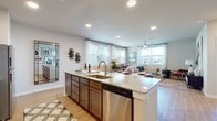 This well-appointed single-floor residence offers a thoughtfully designed open-concept layout that seamlessly connects the kitchen, dining, and living areas. The kitchen serves as the heart of the home, anchored by a generously sized granite-topped island with an undermount sink and stainless steel dishwasher, complemented by rich dark cabinetry, stainless steel appliances, and recessed lighting. Light wood-style flooring flows throughout the main living spaces, enhancing the warm, cohesive aesthetic.

The living room is bright and inviting, featuring multiple windows with sheer curtains that invite abundant natural light, along with a ceiling fan for added comfort. A clean hallway connects the main living areas to the private bedrooms, each offering ceiling fans, large windows with outdoor views, and a calm, restful atmosphere. One bedroom features a soft, neutral palette with a round mirror accent, while the second offers a cozy, eclectic warmth.

The bathroom is finished with granite countertops, dark cabinetry, large-format tile surrounding the soaking tub and shower combination, and direct access to a walk-in closet with built-in shelving. Throughout the residence, neutral wall tones, recessed lighting, and consistent flooring create a cohesive and modern living environment.