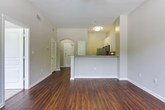 Located in Atlanta's 30327 zip code, this single-story residence presents a well-designed layout with a cohesive, neutral color palette and rich, dark hardwood-style flooring that flows through the main living areas. The open living space is generously proportioned, featuring vaulted ceilings, a ceiling fan, and a glass-panel door flanked by windows that invite abundant natural light and provide outdoor views. White trim and soft gray walls create a bright, clean ambiance throughout.

The kitchen is outfitted with stainless steel Whirlpool appliances, including a refrigerator, electric range, and over-the-range microwave. White shaker-style cabinetry, granite countertops, and a classic subway tile backsplash lend the kitchen a polished, modern character. A breakfast bar connects the kitchen to the living area, enhancing the open-concept flow.

The bathroom continues the home's refined aesthetic with granite-topped white cabinetry, wood-look tile flooring, and a tiled tub-shower combination accented with a mosaic tile detail. The bedroom features carpeted flooring, offering a comfortable contrast to the hardwood-style surfaces found elsewhere in the residence.