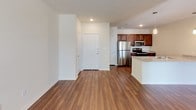 This single-floor residence offers a thoughtfully designed open-concept layout that seamlessly connects the living, dining, and kitchen areas. Rich hardwood-style flooring runs throughout the main living spaces, lending warmth and visual continuity to the interior.

The kitchen is equipped with stainless steel appliances, including a refrigerator, range, microwave, and dishwasher. Rich dark cabinetry provides generous storage, while light granite-style countertops offer ample prep space. A kitchen island with matching countertop serves as both a functional workspace and a casual dining option.

The open living area is bright and welcoming, featuring multiple windows with slatted blinds that allow natural light to filter in. A ceiling fan provides added comfort and airflow. The space flows naturally toward a secondary area or entryway, offering flexible use of the floor plan.

The bedroom is carpeted for comfort, featuring its own ceiling fan and a window with blinds that brings in natural light while maintaining privacy.

The bathroom is finished with classic white subway tile surrounding the soaking tub and shower combination, complemented by brushed nickel fixtures. Hardwood-style flooring continues into the bathroom, maintaining design cohesion throughout the unit.

Overall, the space presents a clean, modern aesthetic with practical finishes suited for comfortable everyday living.
