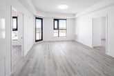 Located on the seventh floor at 30 Hanmer St W in Barrie, Ontario, this unit presents a clean, contemporary design characterized by a bright, all-white interior palette and light-toned laminate flooring throughout. The open-concept kitchen serves as a central feature, equipped with stainless steel appliances including a range, over-the-range microwave, refrigerator, and dishwasher. White shaker-style cabinetry extends to the ceiling, complemented by a neutral-toned countertop and a peninsula with a double undermount sink, creating a functional workspace that flows seamlessly into the living area. Recessed lighting enhances the kitchen's brightness.

The bedrooms are generously proportioned, each featuring large black-framed windows that frame expansive views of the surrounding Barrie landscape, flooding the rooms with natural light. Built-in closet space is present in the bedrooms, adding practical storage. The bathroom is finished in crisp white tones, featuring a vessel sink atop a vanity, a wall-mounted medicine cabinet, and a separate shower enclosure. Light tile flooring completes the clean aesthetic. Throughout the unit, the consistent use of white walls, modern fixtures, and light flooring creates a cohesive, airy ambiance.