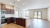 Located in Prosper, TX, this well-appointed 2-bedroom, 2-bathroom unit offers a thoughtfully designed single-floor layout. The open-concept living, dining, and kitchen area serves as the heart of the home, featuring warm hardwood-style flooring, crown molding, and a ceiling fan. French doors lead to an outdoor patio, inviting natural light throughout the space.

The kitchen is equipped with rich dark-wood cabinetry, granite countertops, a center island with a built-in sink, and a full suite of stainless steel appliances including a refrigerator with ice maker, range, microwave, and dishwasher. Recessed lighting adds a polished finish.

The generously sized primary bedroom is carpeted for comfort, includes a ceiling fan, and offers access to multiple closets. Both bathrooms feature granite-topped vanities with dark wood cabinetry, large mirrors, and hardwood-style flooring, with one bathroom including a walk-in shower and grab bars.

The second bedroom also features hardwood-style flooring and crown molding. Additional highlights include a dedicated laundry area, ample closet storage throughout, and a hallway that connects all areas efficiently for a functional, comfortable living experience.