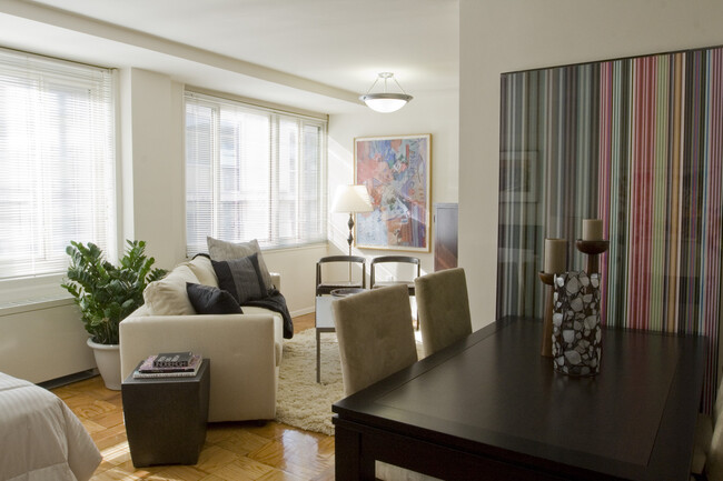 Studio apartment space accommodates both a living room area with a sofa and side tables as well as a dining room area with a standard-size dining table - The Statesman