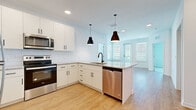Located at 1325 14th St W in Bradenton, FL, this well-appointed 2-bedroom, 2-bathroom unit offers a thoughtfully designed single-floor layout. The open-concept kitchen and living area serves as the heart of the home, featuring crisp white shaker cabinetry, granite countertops, a white subway tile backsplash, and a full suite of stainless steel appliances. A peninsula island with a matte black faucet and pendant lighting above provides additional prep space and a natural gathering point. Light wood-look flooring flows throughout the main living areas, adding warmth to the bright, neutral interior.

The living room benefits from large windows with blinds and a glass door that opens to a private balcony, offering open views of the surrounding Bradenton skyline and lush tree canopy. Both bedrooms are carpeted and filled with natural light; the primary bedroom includes an ensuite bathroom. Each bathroom is finished with granite vanity tops, white cabinetry, matte black hardware, and tiled soaking tub/shower combinations. A dedicated closet provides convenient storage. The clean, modern aesthetic and quality finishes make this a comfortable and functional home in a prime Bradenton location.