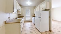 Located at 1505 La Fonda Dr in Las Cruces, New Mexico, this two-bedroom, one-bathroom home offers a straightforward and functional single-floor layout. Light beige tile flooring runs consistently throughout the entire space, creating a cohesive and easy-to-maintain interior.

The galley-style kitchen is well-equipped, featuring white cabinetry both above and below the countertops, a double sink, a gas range, and a full-size refrigerator. A window at the far end of the kitchen allows natural light to brighten the workspace.

Both bedrooms are simply designed with neutral walls, tile flooring, and windows fitted with blinds that let in outside light. The primary bedroom includes a wall-mounted TV bracket, offering a convenient media setup option. The second bedroom provides a quiet, clean space with a view of the surrounding neighborhood.

A dedicated closet with bifold doors adds practical storage, with a separate shelved storage area visible through the hallway. The bathroom includes a tiled tub-shower combination, a toilet, and a vanity with an integrated sink and mirror with overhead lighting.

A textured ceiling is present throughout portions of the home. The overall layout is efficient and well-connected through a central hallway, making the most of the available square footage in this modest Las Cruces residence.