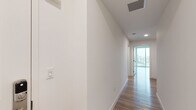 Located at 5401 Lankershim Blvd in North Hollywood, California, this modern single-floor residence showcases a clean, contemporary design throughout. Light wood-tone flooring runs consistently across the unit, contributing to a bright and cohesive aesthetic, while crisp white walls create an open, airy atmosphere.

The kitchen is a standout feature, outfitted with sleek white flat-panel cabinetry, a white subway tile backsplash, quartz countertops, and a full suite of stainless steel appliances including a gas range, microwave, dishwasher, and refrigerator. A peninsula counter provides additional prep space and adds to the kitchen's functional appeal. Recessed lighting and pendant fixtures illuminate the space effectively.

The living area is generously proportioned with smooth white walls and a sliding glass door that opens to a private balcony, offering views of the surrounding North Hollywood neighborhood. The bedrooms are well-sized, with one featuring a large window that fills the room with natural light and another including a built-in closet with rod and shelf storage.

Two bathrooms serve the unit: one with a glass-enclosed walk-in shower and another with a full soaking tub and shower combination. Both feature wood-look flooring and clean white finishes. A hallway connects the private spaces, equipped with ceiling ventilation and recessed lighting for added comfort throughout.
