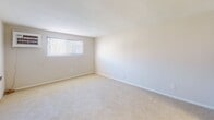 Located at 1 Jefferson St in Clifton Heights, PA, this single-floor unit offers a clean, straightforward layout designed for practical, comfortable living. The interior is finished with neutral white and beige tones throughout, creating a bright and cohesive atmosphere.

The living area is generously sized, featuring wall-to-wall carpet, a floor vent for heating, and a hallway connection that flows into the rest of the unit. Natural light filters in through windows fitted with blinds, giving the space an open and airy feel.

The kitchen is distinct in its warm hardwood-style flooring, providing a pleasant contrast to the carpeted areas. It features white cabinetry, a stainless steel sink with countertop workspace, a refrigerator, and a dishwasher — offering all essential appliances in a compact, efficient layout.

The bedrooms are well-proportioned with plush carpeting, large windows that bring in natural light, and clean white walls. At least one bedroom includes a built-in closet with a rod and shelving, providing ample storage. A wall-mounted air conditioning unit is also present in one of the rooms.

The bathroom is finished with classic white subway tile surrounding the tub and shower, complemented by a curtain rod setup — offering a clean and functional design. Overall, the unit presents a simple, move-in-ready space in a convenient suburban Pennsylvania location.