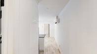Located at 5695 Rue Saint-Jacques in Montréal's Notre-Dame-de-Grâce neighbourhood, this efficiently designed one-bedroom, one-bathroom unit delivers a clean, contemporary aesthetic throughout. Light wood-look flooring runs continuously across the open-plan living and kitchen area, complementing the crisp white walls and recessed lighting that keep the space feeling bright and airy.

The kitchen is a standout feature, anchored by a sleek peninsula with a dark quartz countertop and a matte black faucet and sink. White flat-panel cabinetry reaches toward the ceiling, while stainless steel appliances and a striking navy herringbone tile backsplash add depth and contrast. A large sliding window overlooks an outdoor area, drawing in natural light and providing a pleasant outlook.

The bedroom is a calm, well-proportioned retreat finished in the same light flooring and neutral tones, with its own window that frames a view of the surrounding outdoor space. A baseboard heater ensures year-round comfort.

The bathroom is finished to a high standard, featuring large-format marble-look porcelain floor and wall tiles, a frameless glass shower enclosure with matte black hardware, and a mirrored storage unit. A frosted window allows natural light while maintaining privacy. The cohesive use of modern materials throughout makes this unit a polished and practical urban residence.