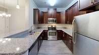 Located at 1701 Island Home Ave in Knoxville, Tennessee, this single-floor residence offers a thoughtfully designed layout with a neutral color palette and a blend of hardwood-style and carpeted flooring throughout. The kitchen is a standout feature, showcasing rich dark wood cabinetry, granite countertops, and a full suite of stainless steel appliances including a refrigerator, range, and microwave. A peninsula with additional counter space provides both prep room and casual seating potential, while an adjacent walk-in pantry adds generous storage. The living area features durable hardwood-style flooring, crown molding, a ceiling fan, and a glass-paned door that invites natural light and provides outdoor access. The bedrooms are carpeted for comfort and each include ceiling fans. At least one bedroom benefits from a spacious walk-in closet with wire shelving, offering ample organization. The bathroom is clean and functional, featuring a tiled tub-shower combination, a granite-topped vanity with dark wood cabinetry, and wood-look flooring. Additional rooms with hardwood-style floors and crown molding details round out a well-finished, move-in-ready interior.