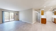 This 2-bedroom, 1-bathroom residence offers a thoughtfully organized single-floor layout with clean, contemporary finishes throughout. Neutral-toned tile flooring flows consistently across all rooms, creating a cohesive and easy-to-maintain aesthetic.

The living room is a generous, open space anchored by a sliding glass door that invites natural light and provides outdoor views of surrounding greenery. Baseboard heating runs along the perimeter, ensuring year-round comfort.

The galley-style kitchen is efficiently designed with warm wood cabinetry, white subway tile backsplash, light countertops, and white appliances including a range, refrigerator, and dishwasher. A double basin sink and recessed lighting add functional detail.

Both bedrooms are well-sized, each featuring windows with outdoor views, individual wall-unit air conditioning, and baseboard heating. The primary bedroom includes a dedicated walk-in closet outfitted with multi-level wire shelving and hanging rods for organized storage. The second bedroom features a built-in sliding-door closet.

The full bathroom is clean and functional, with a tub/shower combination, a wood-toned vanity with a stone-look countertop, and chrome fixtures. The neutral color palette throughout the unit lends a calm, move-in-ready ambiance.