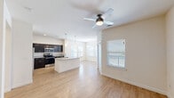 Located at 5212 Daybreak Dr in Killeen, Texas, this single-story, 2-bedroom, 2-bathroom home offers a well-designed open-concept layout that maximizes its comfortable footprint. Light wood-style flooring flows throughout the main living areas, creating a bright and cohesive atmosphere. The living and dining areas are bathed in natural light from multiple windows with white blinds, and a ceiling fan adds both style and function. A chandelier in the dining area adds a touch of elegance. The kitchen is a standout feature, boasting dark cabinetry, granite-style countertops, stainless steel appliances — including a refrigerator, microwave, and range — and a center island with a built-in sink and pendant lighting above. A hallway with built-in open shelving provides convenient storage and connects the main living area to the private quarters. The primary bedroom is generously sized and features a ceiling fan and natural light. The second bedroom is carpeted, bright, and well-proportioned. Both bathrooms are finished with granite-topped dark vanities and wood-style flooring. The primary bath includes a walk-in shower. Additional highlights include two hallways, two closets, and recessed lighting throughout.