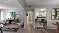 This single-floor residence features 2 bedrooms and 2 bathrooms arranged in a practical, well-organized layout. The open-concept living area is bright and inviting, with light-toned wood-style flooring, neutral gray walls, and a textured ceiling that runs throughout the main living spaces. The living room offers generous room for seating and entertainment, with large drape-framed windows that allow natural light to fill the space. Adjacent to the living room, the dedicated dining area features a pendant light fixture and a window with blinds, creating a pleasant spot for everyday meals. The kitchen connects seamlessly to the main living area via a peninsula countertop with dark granite-style surface and bar seating, complemented by white cabinetry, stainless steel appliances, and pendant lighting. A hallway leads to both bedrooms and bathrooms, providing a clear separation between living and private areas. The primary bedroom is a comfortable, well-sized retreat with carpeted flooring, natural window light, and ample wall space. The second bedroom is similarly appointed. Both bathrooms feature wood-style flooring, white vanities with clean countertops, and a neutral color palette. A closet offers additional storage. The overall ambiance is clean, contemporary, and move-in ready.