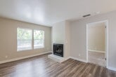 Located at 4305 Norwood Ave in Sacramento, California, this single-story residence offers a well-organized layout with a clean, updated aesthetic throughout. The living area is a welcoming, open space highlighted by wood-look plank flooring, neutral-toned walls, a textured ceiling, and a fireplace set on a raised hearth — providing a functional focal point. Natural light enters through a window fitted with horizontal blinds, creating a bright and comfortable atmosphere. Adjacent to the living area, a peninsula-style kitchen counter serves as a natural divider between the living and kitchen spaces. The galley-style kitchen is efficiently designed, featuring white cabinetry, light quartz countertops, tile backsplash, and a full suite of stainless steel appliances including a gas range, over-the-range microwave, and refrigerator. The bedroom is carpeted and generously proportioned, with two large windows overlooking surrounding greenery, allowing for ample natural light. The bathroom is neatly appointed with wood-look flooring, a white vanity with an integrated sink, a framed mirror, and a full tub and shower combination. The entry area provides a welcoming introduction to the unit, with wood-look flooring continuing seamlessly from the main living space.