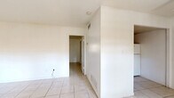 Located at 926 East Fort King Street in Ocala, Florida, this single-story, one-bedroom, one-bathroom unit offers a straightforward and functional layout. Light-colored ceramic tile flooring runs consistently throughout the entire space, creating a cohesive and easy-to-maintain interior.

The main living area combines the living room, dining room, and kitchen into one open-concept space. The living room is bright and airy, featuring two front-facing windows that allow natural light to fill the room, complemented by a ceiling fan overhead. The kitchen is positioned at the rear of this open area and is equipped with warm-toned wooden cabinetry — both upper and lower — a countertop with an integrated sink, and a full-size refrigerator.

A hallway connects the main living area to the private spaces, including the spacious bedroom, which features a window with an outdoor view and two closets providing ample storage. The bathroom includes a vanity with a sink and wood cabinetry, a wall-mounted mirror, a toilet, and a shower-tub combination enclosed by a curtain. Classic octagonal tile flooring adds a distinctive touch to the bathroom floor.

Overall, the unit presents a clean, minimalist interior with white walls throughout, offering a blank canvas ready for personalization.