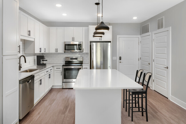 Modern kitchen with white cabinetry, white quartz countertops, and stainless steel appliances - Avalon South End