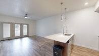 This well-appointed 1-bedroom, 1-bathroom unit offers a thoughtfully designed layout across a single floor, making efficient use of its comfortable footprint. The open-concept kitchen and living area serves as the heart of the unit, where warm wood-look flooring, crisp white walls, and a ceiling fan create a bright and welcoming atmosphere. A door opens to natural light from outside, enhancing the airy feel of the living space.

The kitchen is a standout feature, equipped with a suite of stainless steel appliances including a refrigerator, range, and microwave. Rich walnut-toned cabinetry provides ample storage, while a peninsula with a white quartz countertop and an undermount sink adds both functionality and style. Stylish cylindrical pendant lights hang above the peninsula, adding a modern design touch.

The spacious primary bedroom offers plush carpeting, a window that brings in natural light, and access to a dedicated walk-in closet with wrap-around hanging rods and carpeted flooring — providing generous storage.

The bathroom is clean and contemporary, featuring wood-look tile flooring, a walnut-toned vanity with a white countertop, a large mirror, and a full tub-shower combination with a curved curtain rod. Every detail reflects a cohesive modern aesthetic throughout the unit.