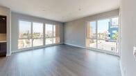 Located at 285 Molino Ave in Long Beach, California, this contemporary single-floor residence showcases modern design and high-quality finishes throughout. Light wood-tone flooring runs seamlessly across the space, complementing the clean, neutral color palette on the walls and ceilings.

The open-concept living area is a standout, featuring floor-to-ceiling sliding glass doors and oversized windows on multiple walls that flood the space with natural light and offer sweeping views of the surrounding Long Beach cityscape, including palm trees and neighboring architecture.

The chef-inspired kitchen is outfitted with rich dark wood cabinetry, crisp white quartz countertops, a geometric tile backsplash, stainless steel appliances including a range, microwave, refrigerator, and dishwasher, along with a large center island ideal for entertaining.

The bedrooms are generously proportioned, each featuring large windows with outdoor views and ample natural light. The bathrooms are elegantly appointed with dark wood vanities, white countertops, frameless glass shower enclosures, and recessed lighting. A hallway laundry closet houses a convenient stacked washer and dryer unit, adding functional ease to this polished, move-in-ready residence.