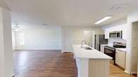 This well-appointed 800-square-foot, one-bedroom, one-bathroom apartment at MacAlpine Place offers a functional and modern single-floor layout. The combined kitchen and living area serves as the heart of the home, featuring hardwood-style flooring, a ceiling fan with light fixture, and multiple windows dressed with horizontal blinds that invite generous natural light. The kitchen is equipped with a full suite of stainless steel appliances, including a refrigerator, electric range, built-in microwave, and dishwasher. White cabinetry and a white countertop peninsula with an integrated sink provide ample storage and prep space. In-unit washer and dryer hookups add everyday convenience. The 150-square-foot bedroom offers hardwood-style flooring, a ceiling fan, and windows on two walls, creating a bright and airy feel. A dedicated closet features built-in wire shelving, maximizing storage efficiency. The bathroom includes a full-size soaking tub and shower combination with white tile surround and chrome fixtures. A hallway connects the main living areas, completing this cohesive and practical floor plan designed for comfortable everyday living.