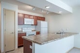 Located at 2864 Pleasant View Rd in Middleton, Wisconsin, this 2-bedroom, 1-bathroom single-floor residence offers a practical and comfortable layout designed for everyday living. The open-concept living and kitchen area forms the heart of the home, where rich cherry wood cabinetry, granite-style countertops, and white appliances — including a range, microwave, and refrigerator — define the kitchen space. A peninsula counter provides a natural transition into the carpeted living room, which is brightened by a ceiling fan, a sliding glass door with vertical blinds, and an additional window that invites natural light. The two bedrooms feature soft wall-to-wall carpeting and neutral tones. The primary bedroom is generously sized and includes a dedicated closet, while the second bedroom offers a bright window with an outdoor view. The full bathroom is well-appointed with rich wood vanity cabinetry, a large mirror with overhead lighting, tile flooring, and a full tub-shower combination. A dedicated in-unit laundry area houses a full-sized washer and dryer, adding everyday convenience. Clean lines, consistent neutral tones, and tile flooring in wet areas give the space a cohesive, move-in-ready aesthetic throughout.