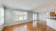 Located in Lewis Center, Ohio, this three-bedroom, three-bathroom home spans three floors, offering a well-organized layout with generous living space across each level. The main living area features warm hardwood-style flooring, recessed lighting, crown molding, and large windows with sliding glass door access that fill the room with natural light. An elegant arched entryway connects the living space to the foyer, which includes a staircase leading to the upper floors. The kitchen is equipped with warm wood cabinetry, dark granite-style countertops, black appliances including a range, microwave, and refrigerator, and is complemented by matching hardwood-style flooring and crown molding throughout. The three bedrooms are carpeted for comfort, with the spacious primary bedroom offering ample room and closet access. Each of the three bathrooms features tile flooring, wood vanities, and tub-shower combinations with brushed nickel fixtures; the primary bath includes a dual-sink vanity. A dedicated laundry room with washer and dryer hookups adds everyday convenience. Multiple closets, hallways, and a utility room round out this thoughtfully designed multi-story home.