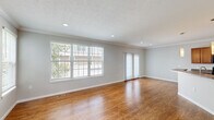 Located in Lewis Center, Ohio, this three-bedroom, three-bathroom home spans three floors, offering a well-organized layout with generous living space across each level. The main living area features warm hardwood-style flooring, recessed lighting, crown molding, and large windows with sliding glass door access that fill the room with natural light. An elegant arched entryway connects the living space to the foyer, which includes a staircase leading to the upper floors. The kitchen is equipped with warm wood cabinetry, dark granite-style countertops, black appliances including a range, microwave, and refrigerator, and is complemented by matching hardwood-style flooring and crown molding throughout. The three bedrooms are carpeted for comfort, with the spacious primary bedroom offering ample room and closet access. Each of the three bathrooms features tile flooring, wood vanities, and tub-shower combinations with brushed nickel fixtures; the primary bath includes a dual-sink vanity. A dedicated laundry room with washer and dryer hookups adds everyday convenience. Multiple closets, hallways, and a utility room round out this thoughtfully designed multi-story home.