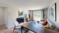 Located at Fifth Ave W in Everett, Washington, this ground-floor unit offers a well-organized single-level layout designed for comfortable everyday living. The living room serves as the heart of the home, featuring a dark-tiled fireplace, wood-look flooring, track lighting, and a large sliding glass door that fills the space with natural light and provides direct access to an outdoor patio with green views. The adjacent dining area is defined by a pendant chandelier overhead and a pass-through opening to the kitchen, creating an open, connected feel. The kitchen is efficiently designed with white cabinetry, light countertops, black appliances including a full-size refrigerator and electric range, and wood-look flooring that carries through from the dining space. The bedroom is carpeted for warmth and comfort, featuring a window with outdoor views and a sliding double-door closet offering generous storage. The bathroom includes a full soaking tub and shower combination with a window for natural ventilation. Neutral wall tones and textured ceilings are consistent throughout, giving the unit a cohesive and understated aesthetic well-suited to a variety of personal styles.
