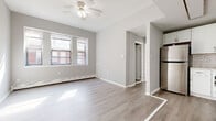 This well-appointed single-floor unit offers a clean, modern aesthetic throughout, characterized by a neutral gray and white color palette, light-toned luxury vinyl plank flooring in the main living areas, and an abundance of natural light streaming through multiple windows. The open living and dining area is a welcoming space anchored by a ceiling fan, large windows that frame views of the surrounding brick buildings, and baseboard heating — creating a bright and comfortable environment. Flowing seamlessly from the living area, the compact kitchen is thoughtfully designed with white shaker-style cabinetry, white subway tile backsplash, marble-look countertops, and a full suite of stainless steel appliances including a gas range, built-in microwave, and refrigerator. The bedrooms are finished with plush wall-to-wall carpeting and feature generous closet space, including double bifold closets in one room, providing ample storage. Each bedroom benefits from natural light through dedicated windows. The bathroom is a standout, boasting decorative patterned floor tile, a classic white vanity, and a full tub-shower combination with white tile surround — blending charm with functionality throughout this move-in ready space.
