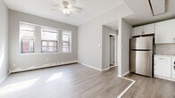 This well-appointed single-floor unit offers a clean, modern aesthetic throughout, characterized by a neutral gray and white color palette, light-toned luxury vinyl plank flooring in the main living areas, and an abundance of natural light streaming through multiple windows. The open living and dining area is a welcoming space anchored by a ceiling fan, large windows that frame views of the surrounding brick buildings, and baseboard heating — creating a bright and comfortable environment. Flowing seamlessly from the living area, the compact kitchen is thoughtfully designed with white shaker-style cabinetry, white subway tile backsplash, marble-look countertops, and a full suite of stainless steel appliances including a gas range, built-in microwave, and refrigerator. The bedrooms are finished with plush wall-to-wall carpeting and feature generous closet space, including double bifold closets in one room, providing ample storage. Each bedroom benefits from natural light through dedicated windows. The bathroom is a standout, boasting decorative patterned floor tile, a classic white vanity, and a full tub-shower combination with white tile surround — blending charm with functionality throughout this move-in ready space.