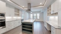 Located at 7395 E Legacy Blvd in Scottsdale, Arizona, this single-floor residence offers a thoughtfully designed layout with high-quality finishes throughout. The centerpiece of the home is a generously sized, open-concept kitchen featuring a large island with built-in shelving, crisp white cabinetry with under-cabinet lighting, granite countertops, stainless steel appliances including a built-in refrigerator and double wall oven, and a striking stainless steel range hood suspended beneath a coffered tray ceiling. Wood-look flooring flows throughout the kitchen and living areas, lending warmth to the clean, contemporary aesthetic. Natural light pours in through multiple windows fitted with blinds, enhancing the airy, open ambiance of the space. The two bathrooms are elegantly finished with patterned tile flooring, dark shaker-style vanities topped with granite countertops, backlit mirrors, and white subway tile walls. The primary bathroom includes a walk-in glass shower, while the secondary bathroom features a tub-shower combination. Bedrooms are carpeted and bathed in natural light from large windows. Two walk-in closets with dual hanging rods provide ample storage. A connecting hallway ties the layout together seamlessly, making this a well-organized and stylish residence in the heart of Scottsdale.