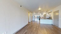 This single-floor unit offers a clean, contemporary design throughout. The open-concept living and kitchen area is anchored by warm hardwood-style flooring that extends across the common spaces. The kitchen is well-appointed with crisp white cabinetry, stainless steel appliances including a refrigerator, electric range, and over-the-range microwave, complemented by granite-look countertops and a mosaic tile backsplash. Pendant lighting over the kitchen island and recessed ceiling lights add both style and functionality to the space.

The bedrooms feature plush wall-to-wall carpeting and ceiling fans, offering a comfortable and quiet retreat. Each bedroom benefits from natural light provided by large windows with blinds, with some rooms offering pleasant outdoor views. The textured ceilings add a subtle design element throughout the sleeping areas.

The bathroom is finished with large-format tile flooring, a white vanity with granite countertops, ample cabinet storage, and a full soaking tub with an integrated shower surround. The layout is practical and efficiently organized. Overall, the unit presents a cohesive, modern aesthetic with thoughtful finishes and a functional floor plan well-suited for everyday living.