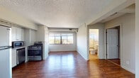 Located on Delmar Boulevard in St. Louis, MO, this single-floor unit offers a thoughtfully laid-out living space with rich hardwood flooring throughout the main areas. The open living and dining space is flooded with natural light through wide, multi-pane windows that frame impressive elevated views of the St. Louis cityscape and the tree-lined Delmar Boulevard below — a standout feature of the unit.

The kitchen is efficiently designed and fully equipped with stainless steel appliances, including a gas range, refrigerator, dishwasher, and microwave. White cabinetry provides ample storage, and the kitchen opens conveniently toward the main living area.

The unit includes two bathroom spaces. The full bathroom features warm terracotta tile flooring, white tile wainscoting, a full bathtub with shower, and a window for natural ventilation. A second combined utility bathroom features matching tile flooring and houses an in-unit washer and dryer — a practical and convenient amenity.

Throughout the unit, textured ceilings add a classic character, while neutral gray-toned walls create a clean, versatile backdrop. The generous layout of the living areas, paired with the panoramic windows, gives the space an airy, open feel with a strong sense of connection to the vibrant neighborhood outside.