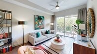 Located at 1115 Town Creek Dr in Austin, TX, this one-bedroom, one-bathroom residence offers a thoughtfully designed open-concept layout. The living room is bright and welcoming, featuring a ceiling fan, dark hardwood-style flooring, and large sliding glass doors that open onto a private balcony with lush tree-lined views. The kitchen is a standout feature, showcasing a lengthy waterfall-edge island with an undermount sink, stainless steel appliances including a French door refrigerator, range, and microwave, two-tone cabinetry in white and slate blue, quartz countertops, and elegant teardrop pendant lighting. Track lighting adds a modern touch overhead. The bedroom offers a comfortable retreat with a ceiling fan, large windows framing green outdoor views, and ample natural light filtered through sheer curtains. The bathroom corridor features large-format tile flooring and leads to both the bathroom and a dedicated closet with built-in shelving. Throughout the residence, neutral walls, wood-look flooring, and contemporary fixtures create a cohesive, modern aesthetic suited to Austin living.