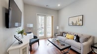 This single-floor residence offers a thoughtfully designed layout that balances comfort and functionality across its key living areas. The living room serves as the heart of the space, featuring warm hardwood flooring, neutral gray walls, and recessed lighting that creates a welcoming ambiance. A tiled fireplace anchors one wall, while a set of French doors floods the room with natural light and provides access to an outdoor balcony with views of the surrounding community. The kitchen is well-equipped with white shaker-style cabinetry, granite countertops, a classic subway tile backsplash, and a full suite of stainless steel appliances including a gas range, microwave, and refrigerator. Hardwood flooring continues seamlessly from the living area into the kitchen, reinforcing a cohesive aesthetic throughout. The bedroom is a serene retreat, carpeted for added comfort, with multiple windows that invite natural light. White furniture and soft, neutral tones give the room a calm and restful character. The bathroom is finished with tile flooring, a tub-shower combination with full tile surround, a granite-topped vanity with white cabinetry, and convenient closet space adjacent to the entry. Overall, this residence presents a clean, modern design with consistent finishes and a practical, well-connected floor plan.
