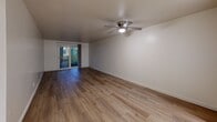 Located at 10728 NE Halsey St in Portland, Oregon, this single-floor, two-bedroom, one-bathroom unit offers a practical and comfortable layout across a well-utilized footprint. The open living room is a standout feature, showcasing warm wood-look flooring, a textured ceiling, a ceiling fan with light fixture, and a sliding glass door that invites natural light and provides access to an outdoor area. The kitchen is partially separated by a structural column and features white cabinetry, light countertops, and a full-size refrigerator, creating a clean and functional workspace. A connecting hallway links the main living areas to the private quarters. Both bedrooms are carpeted in neutral tones and include sliding double-door closets, textured ceilings, and ceiling-mounted light fixtures. The primary bedroom offers a generous footprint with ample closet space, while the second bedroom features a window with vertical blinds that frames an outdoor view. The bathroom is finished with light wood-look flooring, a white vanity, and a full tub and shower combination. With four closets throughout, storage is plentiful. The unit's clean, neutral palette and functional design make it a versatile and move-in-ready space.