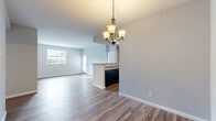 Located at 7053 Grandeur Pl in Union, Kentucky, this well-appointed two-bedroom, two-bathroom single-floor home offers a thoughtfully designed layout across a comfortable footprint. The open-concept living and dining area forms the heart of the home, anchored by rich hardwood-style flooring and neutral gray walls that create a bright, cohesive atmosphere. A stylish chandelier hangs above the dining space, adding a warm, decorative touch. The kitchen features dark espresso cabinetry, stone-look countertops, and black appliances, seamlessly connected to the main living area through a peninsula-style opening. The living room is bathed in natural light from a large window, with views to the outdoors. Both bedrooms are carpeted for comfort, with the primary bedroom offering generous proportions and access to ample closet space — five closets are distributed throughout the home, including walk-in style storage with wire shelving. The primary bathroom includes a glass-enclosed shower, tile flooring, a dark wood vanity, and a broad countertop. A dedicated laundry room with utility hookups and shelving adds everyday convenience. A private balcony extends the living space outdoors, rounding out this functional and move-in-ready home.