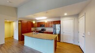 This single-floor residence is designed with an open-concept layout that seamlessly connects the kitchen and living areas, creating a cohesive and functional living environment. The kitchen serves as a central highlight, featuring warm medium-toned cabinetry that extends to the ceiling for ample storage, granite countertops, and a full suite of stainless steel appliances including a refrigerator, range, and microwave. A large center island with a matching granite surface and an integrated sink provides additional workspace and casual seating potential. Pendant lighting above the island, combined with recessed ceiling lights, ensures the kitchen is well-lit and inviting.

The living area flows directly from the kitchen and is characterized by wood-style flooring, neutral wall tones, and vaulted ceilings that lend a sense of openness. A sliding glass door leads to an outdoor space, allowing natural light to fill the room. The bedroom is carpeted and comfortably sized, with a window offering natural light and a closet for storage. The bathroom features granite countertops, an undermount sink with chrome fixtures, a full-size tub and shower combination, and recessed lighting. Overall, the space maintains a clean, modern aesthetic throughout.