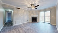 This single-floor, 2-bedroom, 2-bathroom home in Tuscaloosa, Alabama offers a well-designed layout with consistent wood-look luxury vinyl flooring running throughout the entire space. The living room serves as the centerpiece of the home, highlighted by a classic fireplace with a white mantle, crown molding, a ceiling fan with light fixture, and large sliding glass doors fitted with vertical blinds that allow ample natural light to flow in. An adjoining area features a second ceiling fan and a chandelier, creating a seamless transition to the dining space. The galley-style kitchen is efficiently designed with white cabinetry, brushed nickel hardware, light countertops, a sink, and black appliances including a range and refrigerator, complemented by overhead lighting. Both bedrooms are generously sized, featuring neutral-toned walls, large windows with blinds for natural light and privacy, and the same cohesive flooring found throughout the home. The two bathrooms are clean and functional, each offering a vanity with storage, a tub-shower combination, and a mirror. The overall aesthetic is neutral and move-in ready, with a bright, consistent palette that provides a welcoming and versatile living environment.