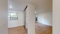 Located at 150 Graylawn Ave in Petaluma, CA, this single-story unit offers a well-organized layout comprising one bedroom, a kitchen, and two hallways connecting the living spaces. The interior features light wood-tone flooring throughout the main living areas, complemented by clean white walls that create a bright and airy atmosphere. The living area is equipped with a ceiling fan and a wall-mounted HVAC unit, providing year-round comfort. The kitchen is thoughtfully designed with white shaker-style cabinetry extending to the ceiling for ample storage, neutral countertops, and stainless steel appliances including a refrigerator, electric range, and over-the-range microwave. The bedroom is carpeted for comfort and features a sliding mirrored closet with built-in shelving, maximizing storage options. A large window in the bedroom frames views of mature trees, bringing in natural light and a connection to the surrounding greenery. A second open area adjacent to the bedroom offers additional flexible space, also benefiting from natural light through multiple windows. The overall design is clean and modern, with a neutral palette that creates a cohesive and welcoming environment throughout.