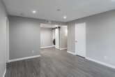 Located at 8655 Arlington Ave in Riverside, CA, this single-story 2-bedroom, 2-bathroom unit offers a clean, modern aesthetic with a practical and well-organized floor plan. Consistent light-toned luxury vinyl plank flooring runs throughout the living areas, complemented by neutral warm-gray walls and crisp white baseboards that create a bright, cohesive look.

The living room is an open, inviting space featuring recessed lighting and a large window dressed with vertical blinds that allow natural light to filter in. The kitchen is efficiently designed in a galley style, equipped with stainless steel appliances — including a refrigerator, range, and over-the-range microwave — paired with white cabinetry, dark countertops, and a skylight overhead that enhances natural illumination.

Both bedrooms offer comfortable proportions, with the primary bedroom providing ample space. Each bedroom features sliding closet doors and windows that bring in natural light. The second bedroom includes rich, darker-toned LVP flooring, adding a subtle design contrast. Both bathrooms are outfitted with full tub-shower combinations, chrome fixtures, and clean white tile surrounds. A dedicated in-unit laundry area with a stacked washer and dryer, accessible via a barn-style door, adds notable everyday convenience.