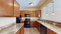 Located at 1300 Community Way in Lancaster, Ohio, this two-floor home offers a well-designed layout with functional living spaces spread across both levels. The main floor features a bright, open living area with light hardwood-style flooring and a sliding glass door that floods the room with natural light and provides outdoor access. The kitchen is a standout, equipped with rich medium-toned wood cabinetry, granite-style countertops, black appliances including a range, built-in microwave, refrigerator, and dishwasher, and a peninsula with pendant lighting overhead. A closet-lined hallway connects the kitchen area to the rest of the main floor, offering generous storage. The upper level hosts the bedrooms, each featuring plush carpeting, vaulted ceilings, and windows with blinds that invite in natural light. The bathrooms are clean and functional — one includes a walk-in glass-door shower with white tile surround, while another features a full tub-shower combination, both with wood-style flooring and warm wall tones. Throughout, the home maintains a consistent, neutral color palette with cream-toned walls, white trim, and warm wood finishes, creating a cohesive and welcoming atmosphere across all rooms.