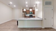 This single-floor unit in Asheville, NC offers a well-designed open layout that connects the kitchen, dining, and living areas into a cohesive, functional living space. The kitchen serves as a central highlight, anchored by a large peninsula with granite countertops and an undermount sink, illuminated by a trio of pendant lights overhead. Warm-toned wood cabinetry extends to the ceiling, providing ample storage, while a full suite of stainless steel appliances—including a refrigerator, electric range, and built-in microwave—completes the space. A subway tile backsplash in soft green adds a subtle decorative touch.

Wood-look flooring flows consistently throughout the unit, lending a cohesive and easy-to-maintain aesthetic. The living area receives natural light through windows and a glass door that opens to an outdoor balcony, complemented by a ceiling fan for year-round comfort. Neutral wall tones and clean white trim keep the interior feeling bright and open.

The bathroom features a full tub and shower combination with built-in shelving, a wood-vanity with granite countertop, an undermount sink, and a framed mirror—all finished with the same wood-look flooring found throughout the unit.