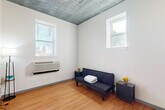 Located at 4015 W 16th Ave in Denver, CO, this one-bedroom, one-bathroom unit offers an efficient and well-organized layout across a single floor. The space showcases an industrial aesthetic with distinctive textured metal ceilings and exposed ductwork, complemented by clean white walls and warm hardwood flooring throughout the main living areas.

The open kitchen is equipped with dark espresso cabinetry, black appliances including a full-size refrigerator, gas range, microwave, and dishwasher, all set against light countertops. Exposed ceiling ductwork adds an urban, loft-inspired character to this functional cooking space.

The living area flows naturally from the kitchen, featuring hardwood floors and multiple windows that invite natural light. The bedroom is carpeted for comfort, offering a quiet retreat with its own windows and direct access to a hallway connecting to the bathroom and utility areas. The bathroom is finished in crisp white, featuring a full tub-shower combination with chrome fixtures and built-in shelving for added convenience.

A hallway and utility room round out the floor plan, providing practical storage and organization. Throughout the unit, the combination of industrial ceiling details, natural light from well-placed windows, and consistent neutral tones creates a cohesive and functional urban living environment.