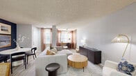 Located at 2848 Caribbean Isle Blvd in Melbourne, Florida, this one-bedroom, two-bathroom residence offers a well-designed, single-story layout with light wood-style flooring and a neutral color palette throughout. The open-concept living room is bright and inviting, featuring multiple windows with warm-toned curtains, a ceiling fan, and a textured ceiling. The space flows seamlessly into a dedicated dining area and a galley-style kitchen outfitted with white cabinetry, stainless steel appliances including a refrigerator, range, and over-the-range microwave, a tile backsplash, and a stainless steel sink with ample counter space. The bedroom is a comfortable retreat accented by a soft blue feature wall, ceiling fan, and a window allowing for natural light. It is supported by two closets, including a walk-in closet with built-in shelving and hanging rods for generous storage. Both bathrooms are finished in a clean, white aesthetic with modern vanities, large mirrors, and tub-shower combinations. A dedicated in-unit laundry area houses a full-size washer and dryer. The overall ambiance is modern yet cozy, with consistent finishes that create a cohesive and functional living environment.